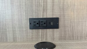 A wall-mounted electrical outlet with two sockets and a USB port, and a circular object below it. - Red Roof Reno (Reno)
