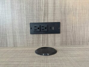 A wall-mounted electrical outlet with two sockets and a USB port, and a circular object below it. - Red Roof Reno (Reno)