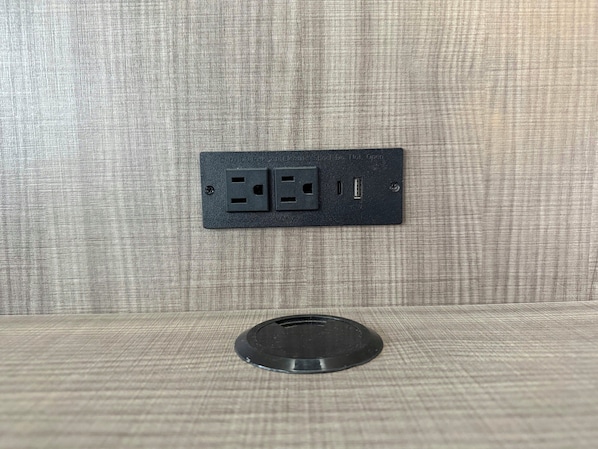 A wall-mounted electrical outlet with two sockets and a USB port, and a circular object below it. - Red Roof Reno (Reno)