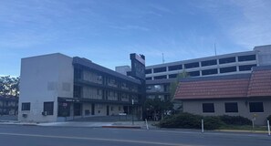 A multi-story building with a gated entrance, a parking garage, and a small adjacent building with a red roof. - Red Roof Inn Reno (Reno)