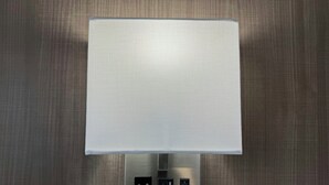 A wall-mounted light fixture with a textured shade and a control panel with three buttons. - Red Roof Reno (Reno)