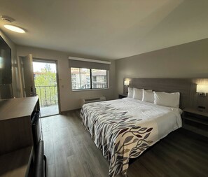 Une chambre avec un grand lit, un bureau, une fenêtre et un balcon.