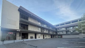 A multi-story building with an office on the ground floor, balconies, and a parking lot.