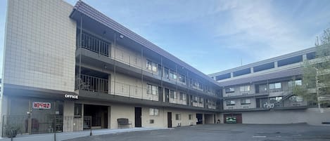 A multi-story building with an office on the ground floor, balconies, and a parking lot.