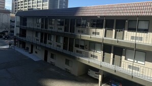 A multi-story building with balconies, a parking area, and a clear sky. - Red Roof Reno (Reno)