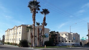 A multi-story hotel with a sign for Bayshore Inn, a parking lot, and palm trees. - Bayshore Inn (Laughlin)