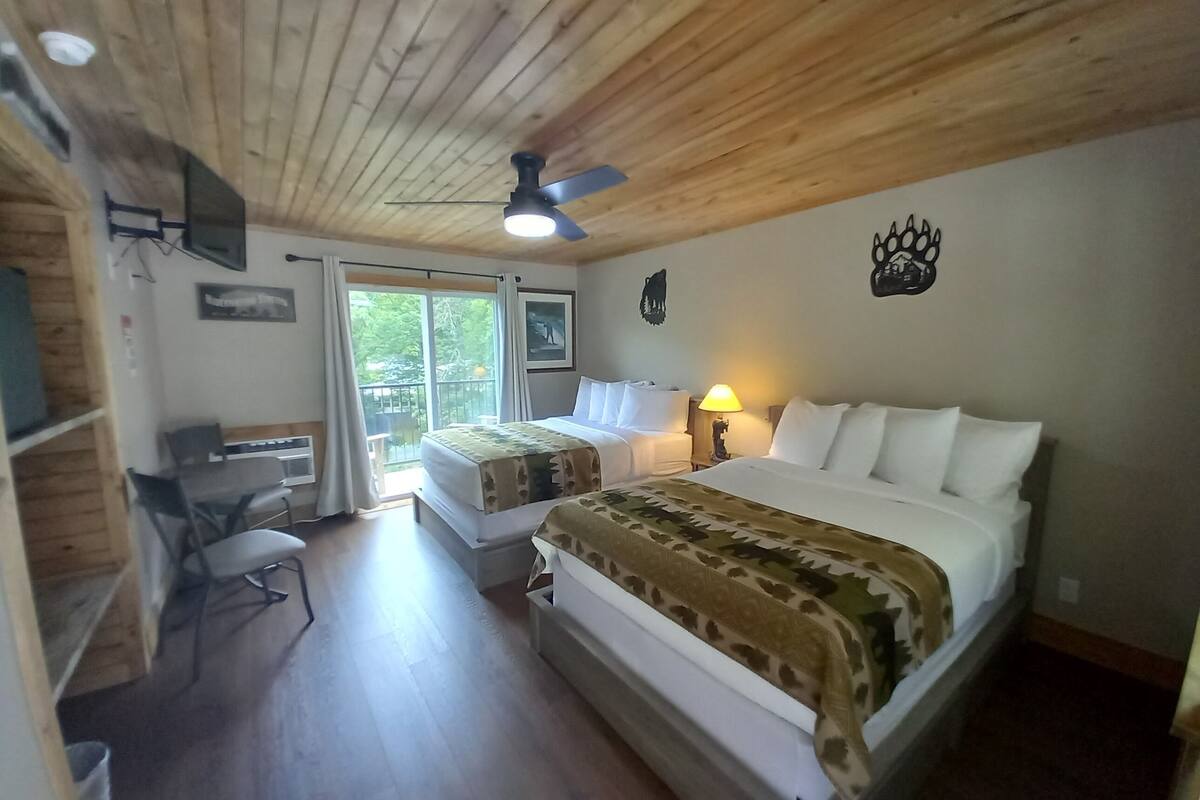 Ein Schlafzimmer mit einem großen Bett, einem Schreibtisch und einem Stuhl. Es gibt einen Deckenventilator und ein Fenster mit Vorhängen.