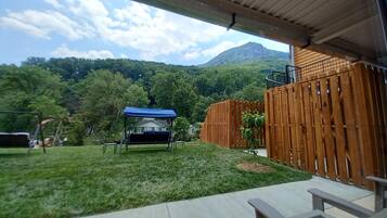 A covered patio area with a wooden fence, a swing set, and a small garden.
