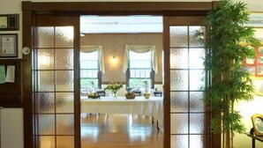 Una habitación con puerta de madera que da a un comedor con una mesa lista para una comida.