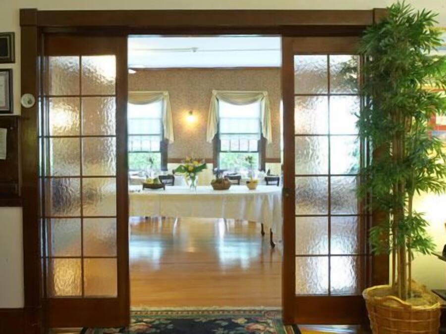 Una habitación con puerta de madera que da a un comedor con una mesa lista para una comida.