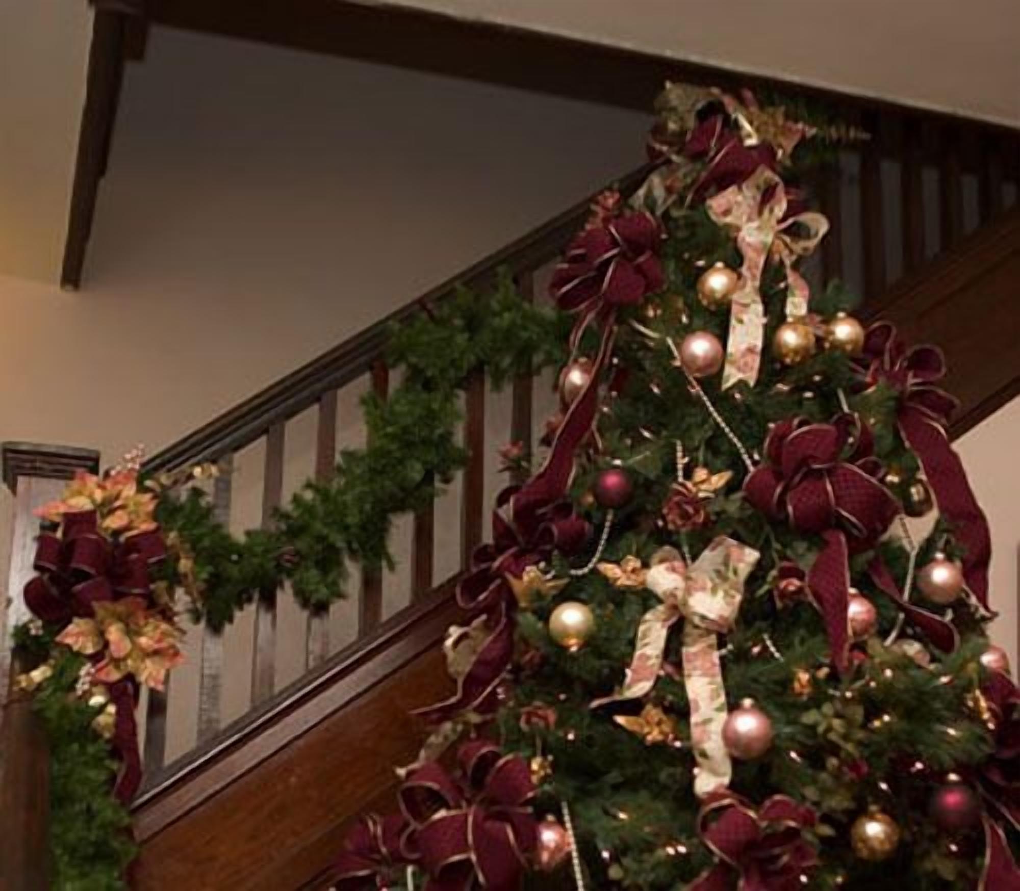 A staircase with a Christmas tree decorated with red and gold ornaments and ribbons.