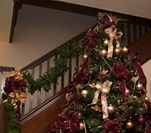 A staircase with a Christmas tree decorated with red and gold ornaments and ribbons.