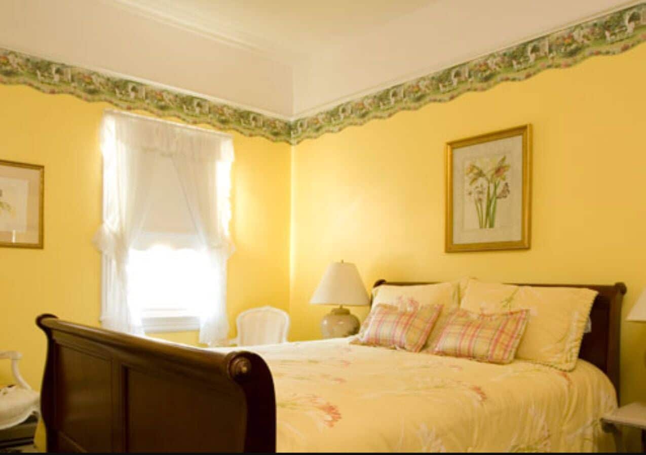 A bedroom with a bed, a chair, a lamp, and a window with curtains.