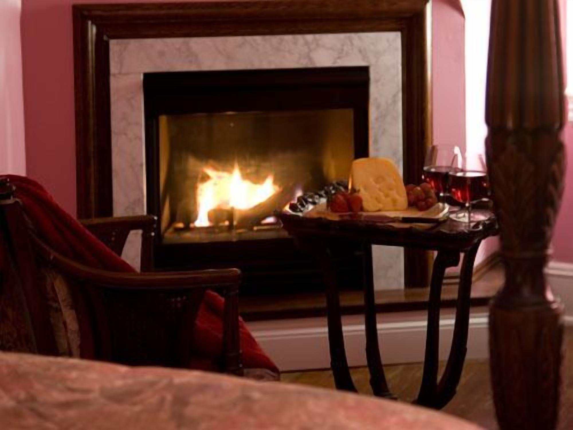 Una habitación acogedora con chimenea, una mesa con comida y bebidas, y una silla.