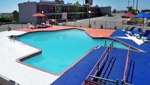 A swimming pool with a star-shaped design, surrounded by lounge chairs and umbrellas. - Big Texan Motel (Amarillo)