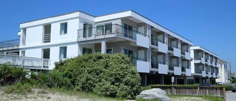 A modern multi-story hotel with balconies and a beach view.