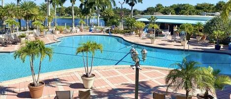 A pool area with palm trees, lounge chairs, and a view of the water.