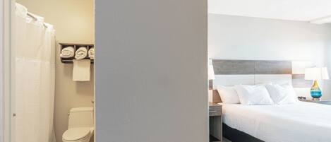 Habitación de hotel con inodoro, cortina de ducha y cama con almohadas y lámpara.