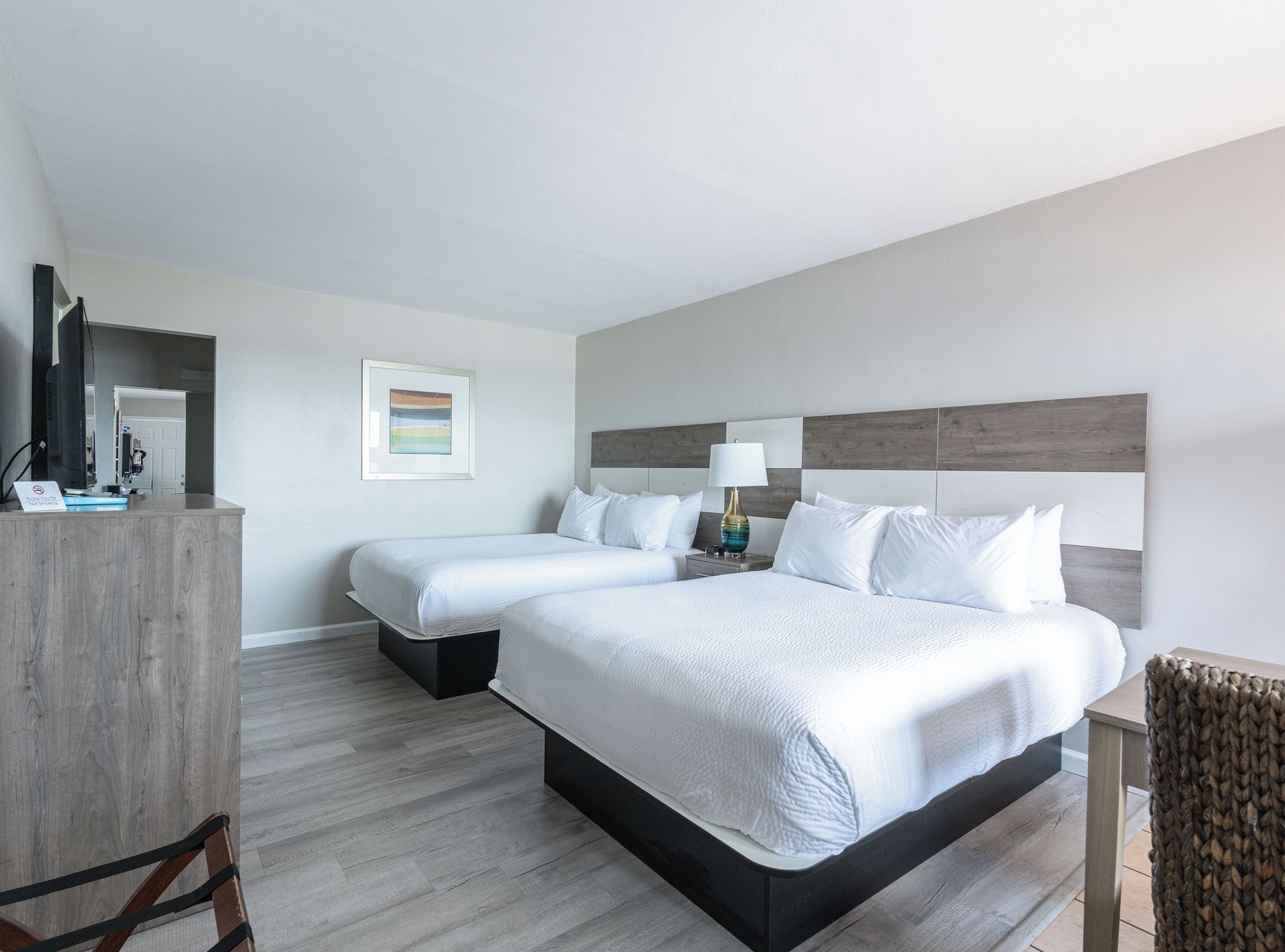 A hotel room with two beds, a desk, and a chair.