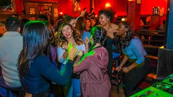 A crowded indoor setting with people interacting closely, possibly at a social event or party.