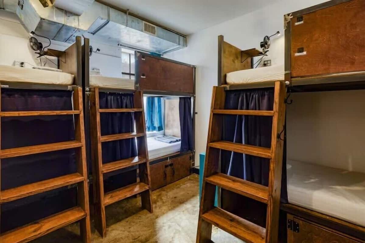 Bunk beds with wooden frames and curtains, a window with curtains, and a ceiling fan.