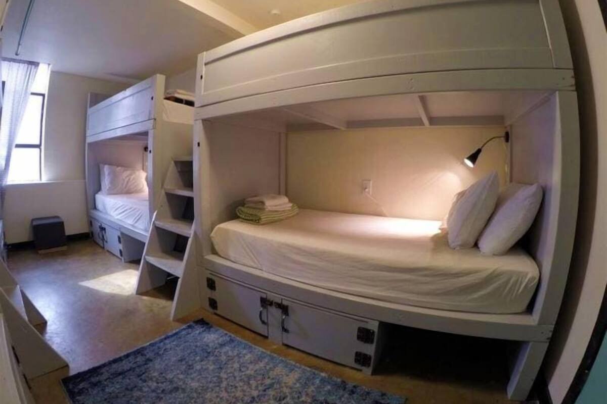 A bunk bed room with a desk, a lamp, and a window.