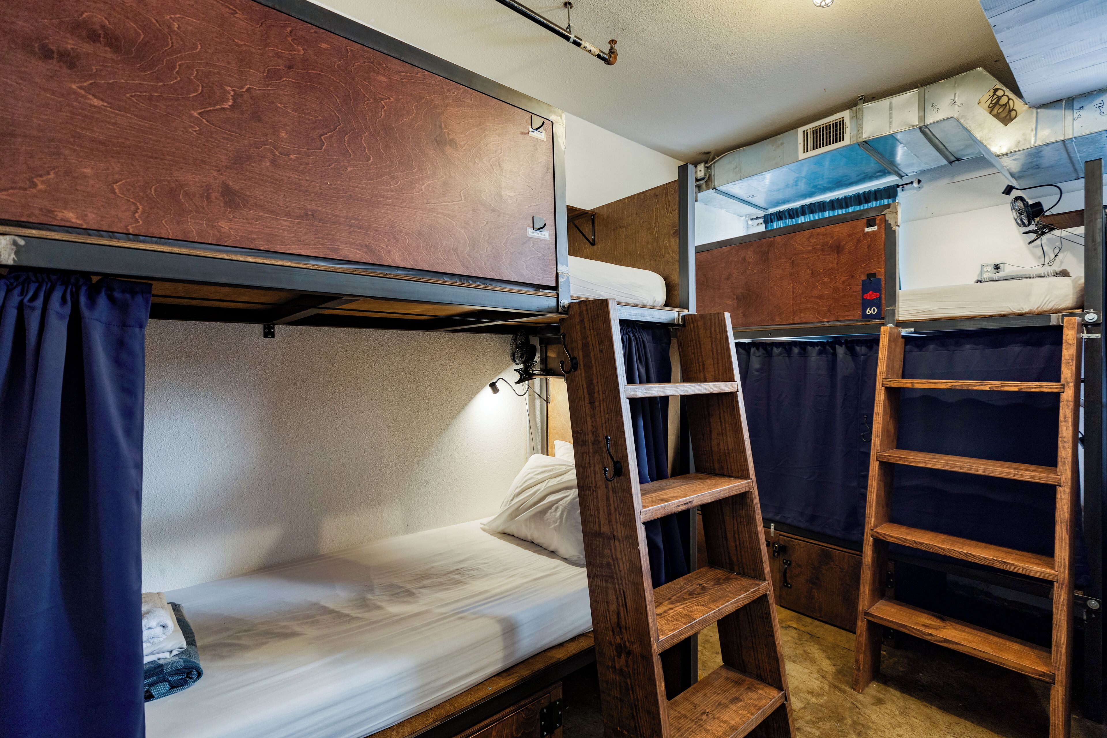 Une pièce compacte et bien éclairée, avec des lits superposés, une échelle en bois et une petite étagère.