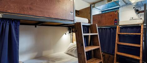 Une pièce compacte et bien éclairée, avec des lits superposés, une échelle en bois et une petite étagère.
