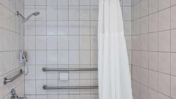 A shower area with a white bathtub, a handheld showerhead, and a grab bar.