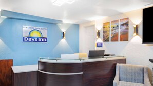 Ein Empfangsschalter mit dem Logo von Days Inn, einem Laptop und einem Schild mit der Aufschrift 'Anwesender Manager'.