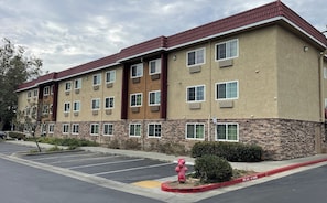 A multi-story hotel with a parking lot and a fire hydrant. - Red Roof Inn Hayward (Hayward)