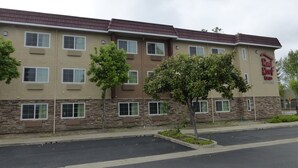 A Red Roof Inn building with multiple windows, a stone facade, and a parking lot. - Red Roof Inn Hayward (Hayward)