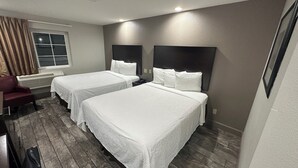Une chambre d’hôtel avec deux lits simples, une chaise rouge, un radiateur et une fenêtre avec des rideaux.