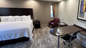 A hotel room with a bed, a desk, a chair, and a window with curtains. - Red Roof Inn Hayward (Hayward)