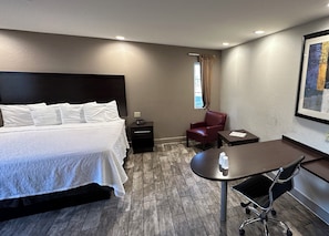 A hotel room with a bed, a desk, a chair, and a window with curtains. - Red Roof Inn Hayward (Hayward)