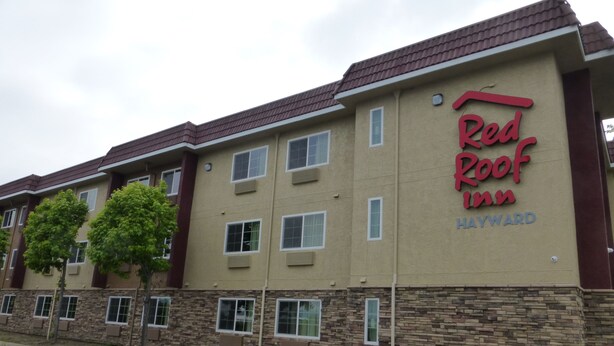 A Red Roof Inn building with a stone facade and multiple windows. - Red Roof Inn Hayward (Hayward)
