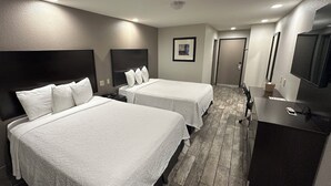 A hotel room with two beds, a desk, a TV, and a door leading to another room. - Red Roof Inn Hayward (Hayward)