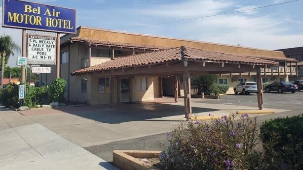Un motel con un cartello pubblicitario, un'area di parcheggio coperta e cielo sereno.