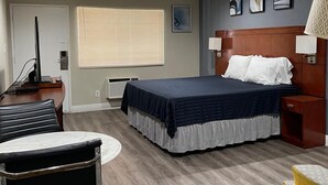 Una camera d'albergo con un letto, una scrivania, una sedia e una finestra con tende.