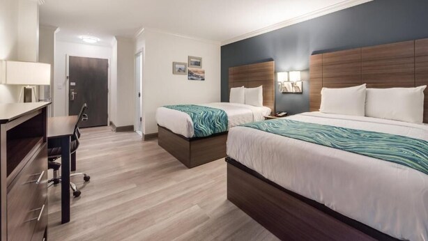 Une chambre d’hôtel avec deux lits, un bureau et une chaise.