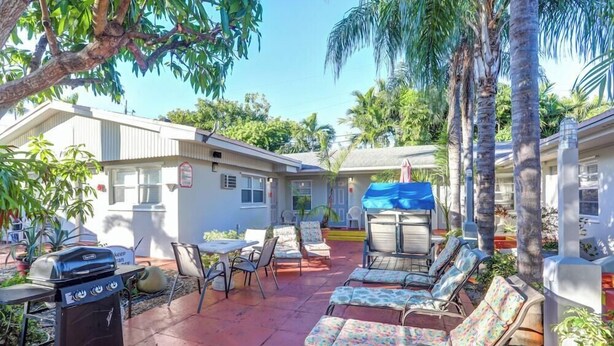 A patio area with outdoor seating, a grill, and a covered table. - Richard s Motel Extended Stay (Hallandale Beach)