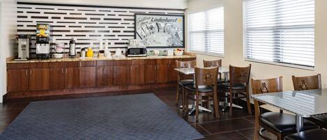 A modern kitchen with wooden cabinets, a built-in microwave, and a coffee station.