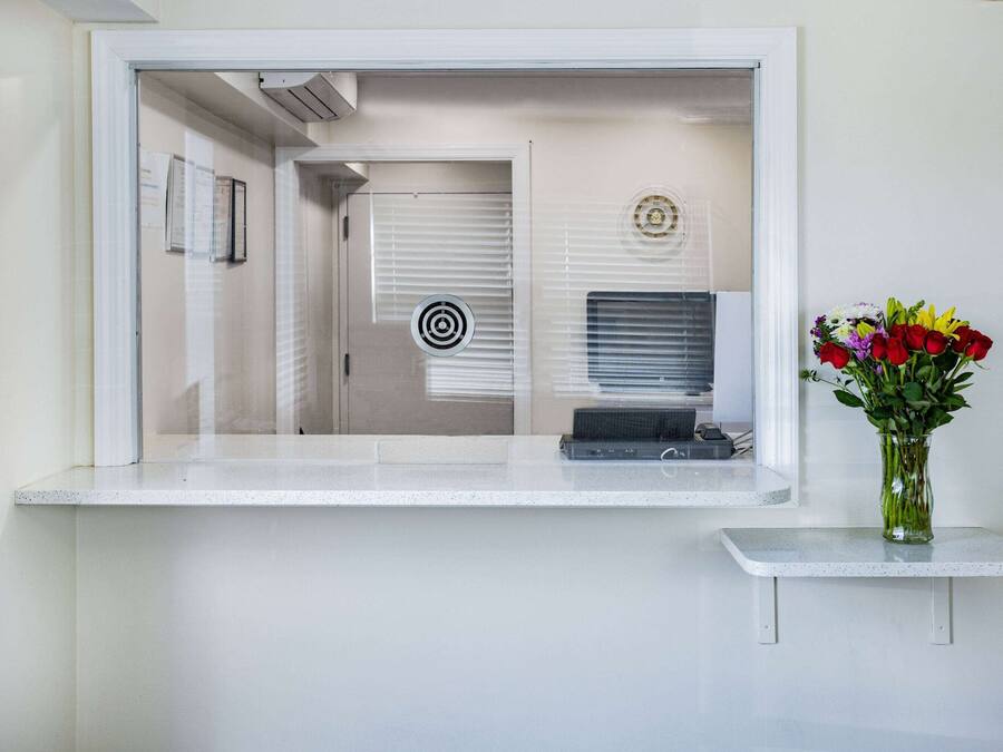 A reception area with a counter, a vase with flowers, and a door with blinds.
