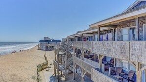 A beachfront hotel with multiple balconies, wooden deck, and ocean views. - Lighthouse View Oceanfront Lodging (Buxton)