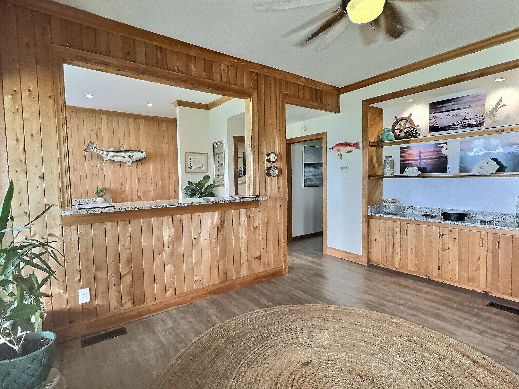 Un intérieur en bois comprenant un comptoir d’accueil, un ventilateur de plafond et un coin cuisine avec des armoires en bois.