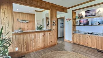 A wooden interior with a reception desk, a ceiling fan, and a kitchen area with wooden cabinets.