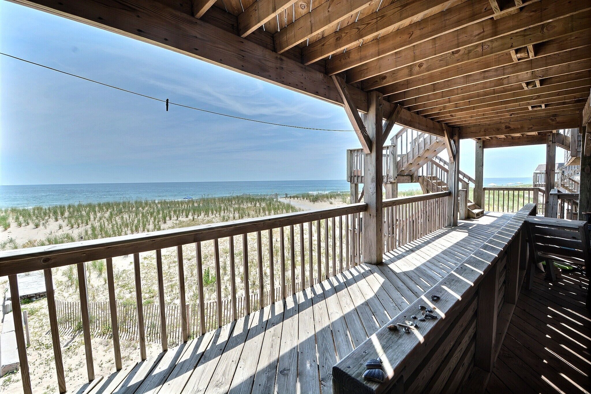 A wooden deck with a view of the beach and ocean.