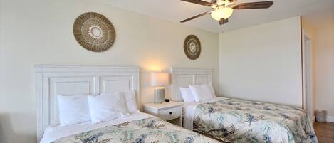 A hotel room with two beds, a ceiling fan, and decorative wall art.