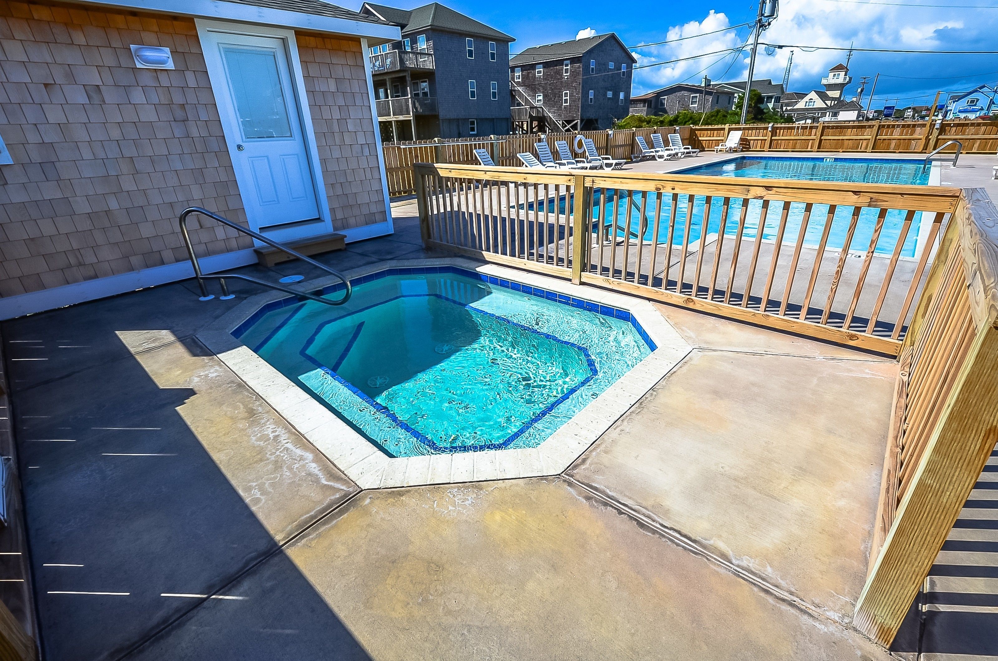 A swimming pool with a wooden deck and lounge chairs, surrounded by a wooden fence.