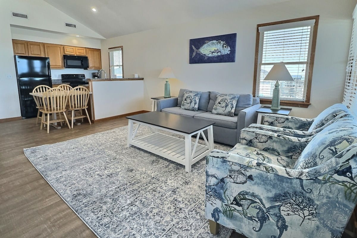 A modern living room with a sofa, coffee table, and dining area.